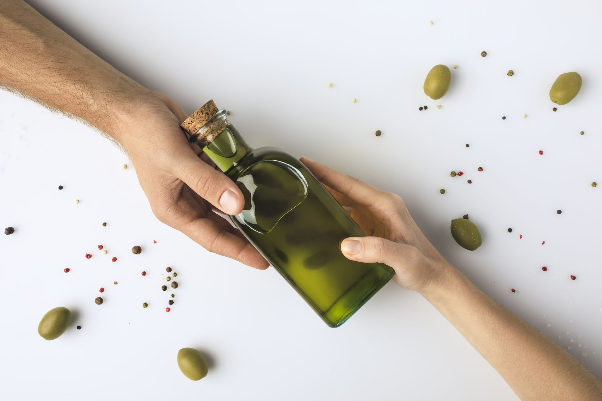 Оливковое масло замерзло в холодильнике. Оливковое масло. Бутылка оливкового масла. Бутылка в руке. Стеклянная бутылка в руке.