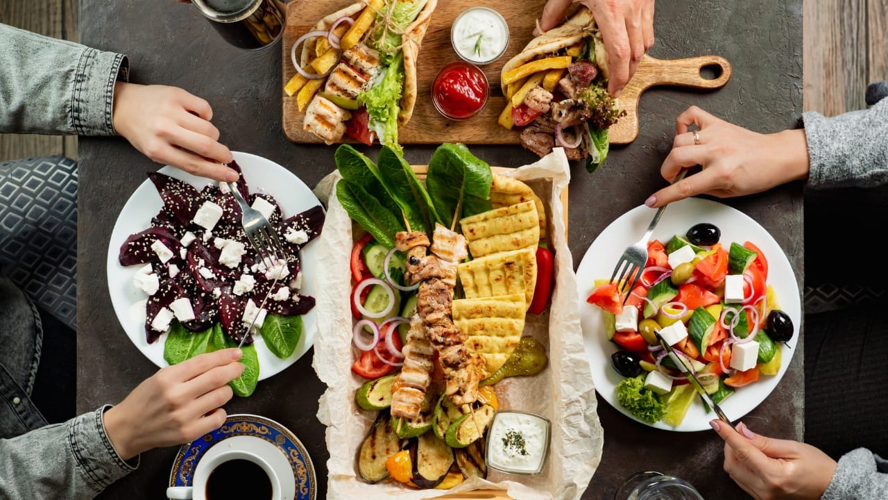 People enjoying a Mediterranean meal including a Greek Village Salad together.