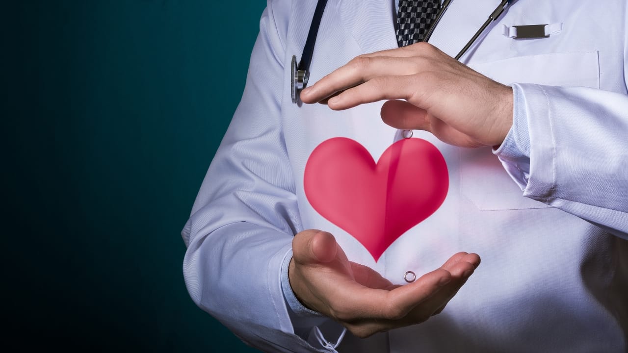 Symbolizing care: A doctor holds a paper heart over the human heart area.