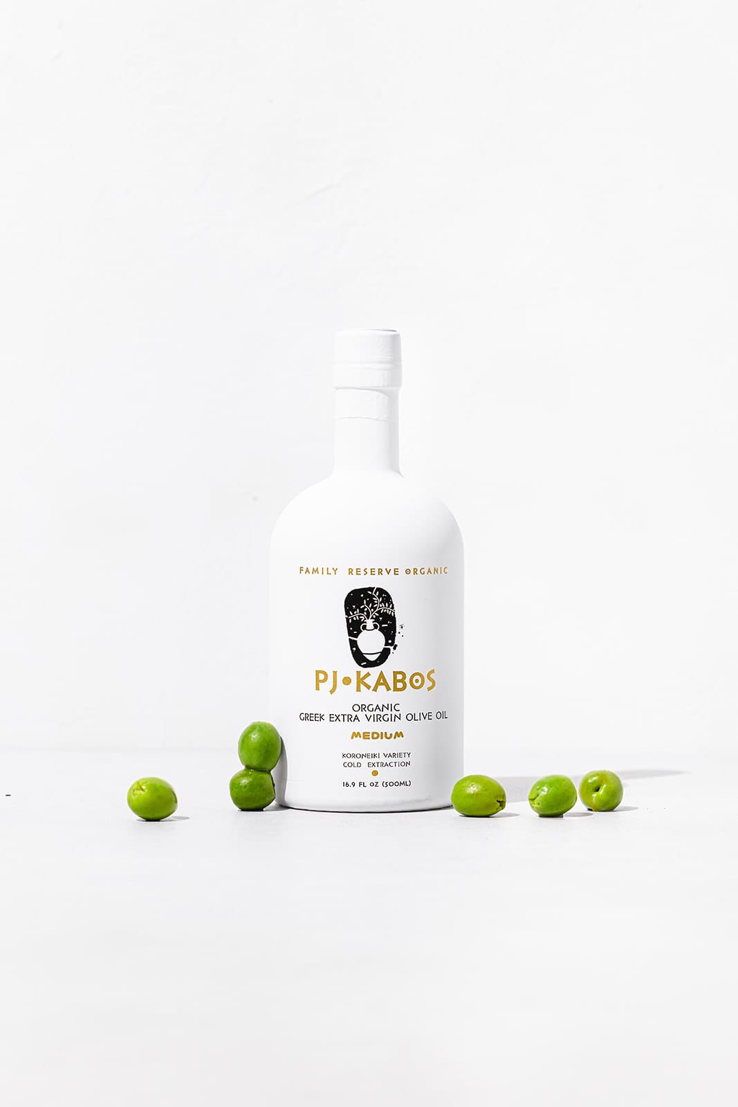 A white bottle of PJ Kabos high-phenolic medium taste intensity and organic extra virgin olive oil with olives scattered around it.