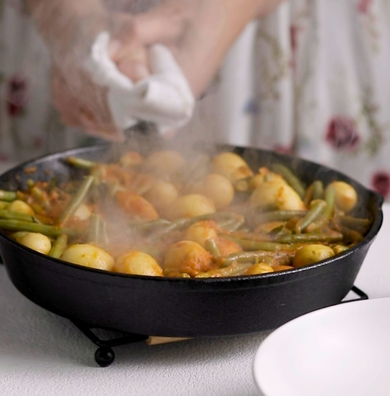 Steam is rising from a pan of braised green beans. It is a mood-evoking comfort photo showing delicious food is almost ready to eat.